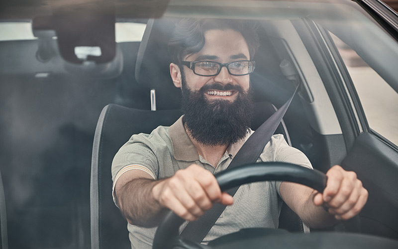 Homme barbu souriant au volant d'une voiture