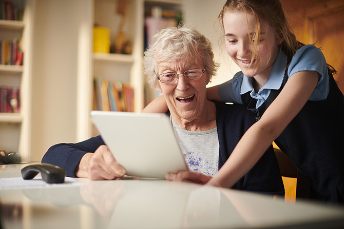 Photo d'une grand-mère avec sa petite-fille utilisant une tablette numérique